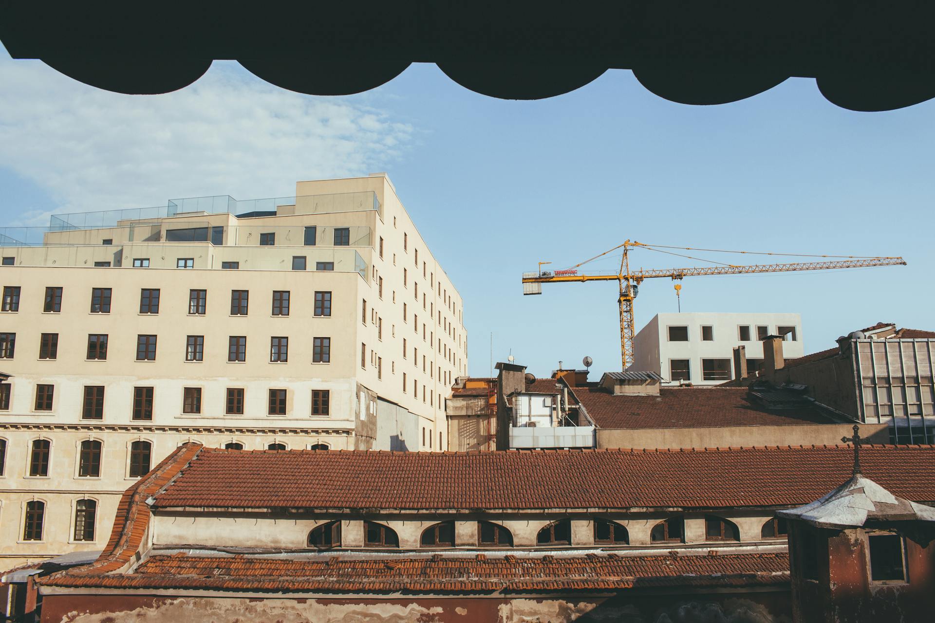 City skyline with buildings and a crane against a clear sky.