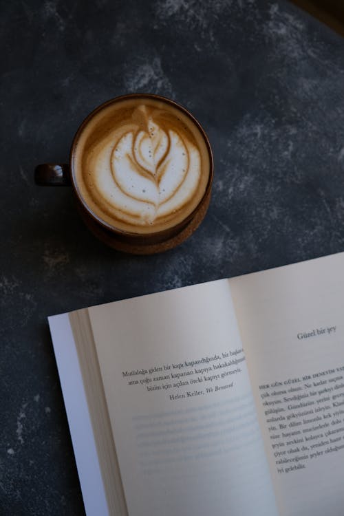 A book with a latte art on it and a cup of coffee