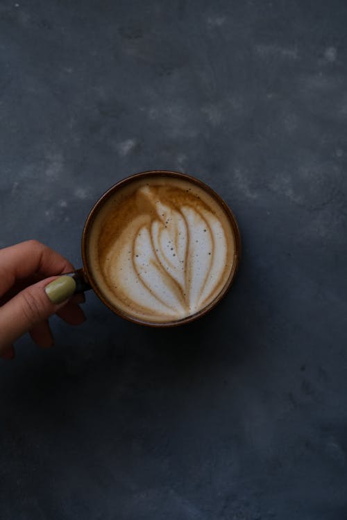 A person's hand holding a cup of coffee
