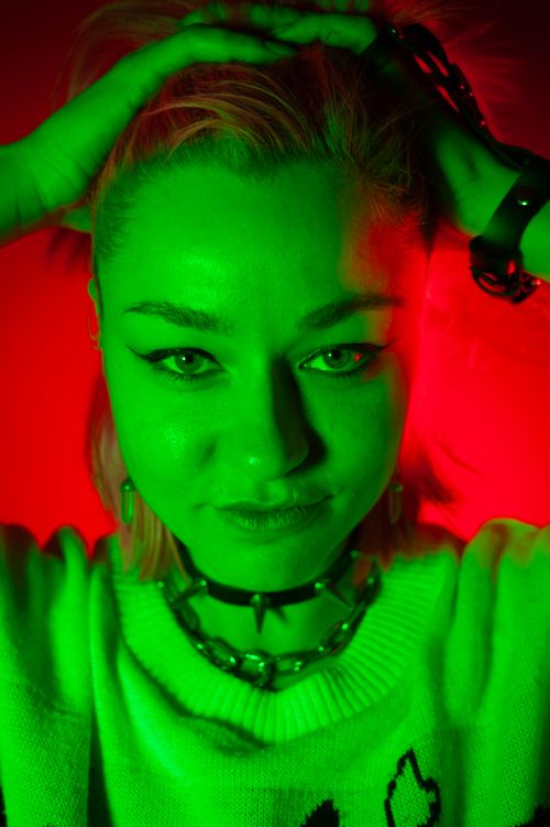 Free Dynamic portrait of a woman with bold green and red lighting creating an edgy look. Stock Photo