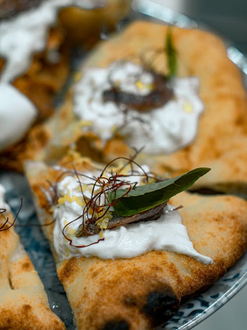 A plate with a pizza with cream and herbs