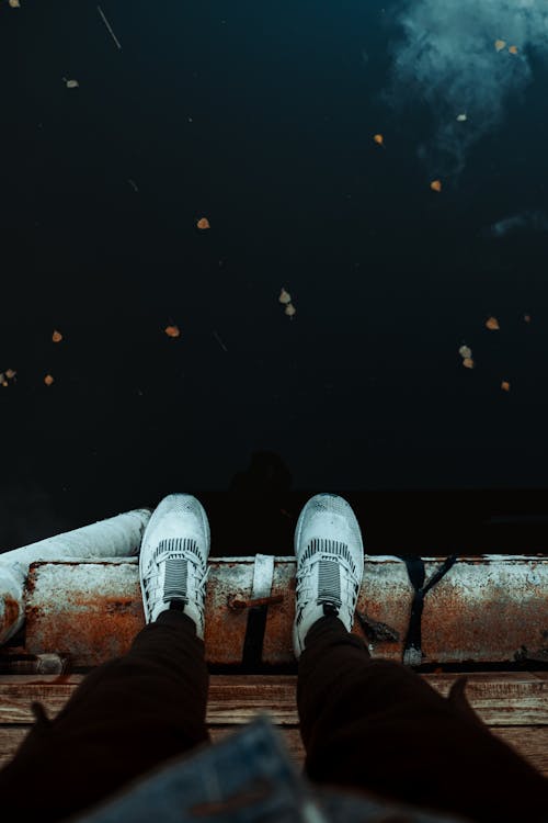 A person's feet are on a wooden dock with a view of the sky