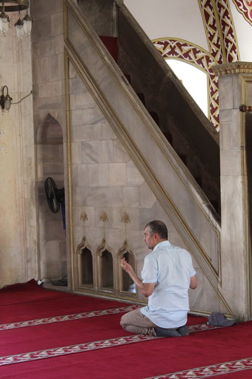 A man kneeling on the floor in front of a mosque