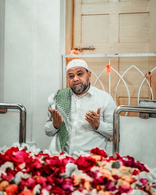 Free A Muslim man praying in front of a bed of colorful flowers indoors. Spiritual reflection scene. Stock Photo