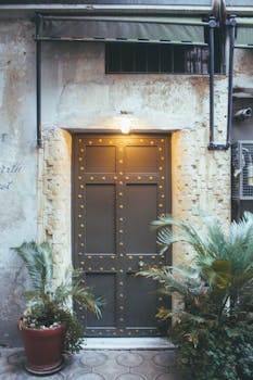 一扇装饰着金属钉的复古门，坐落在乡村风格的外部场景中，四周环绕着郁郁葱葱的绿植