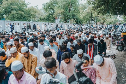 A large group of people engaged in communal prayer on city streets, creating a vibrant urban scene.