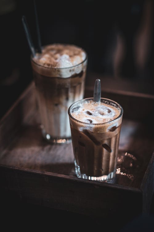 Two iced coffee drinks on a wooden tray