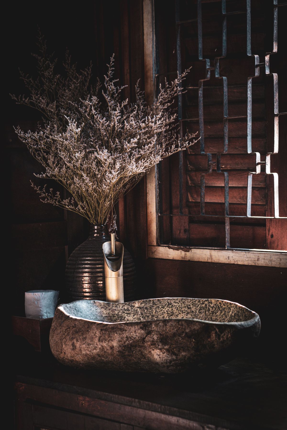 Natural stone basin and decorative vases in a rustic bathroom create an inviting and stylish ambiance. Stock Photo.