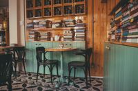 Cafe with wooden bookshelves and small tables, photo by Emre Can Acer on Pexels
