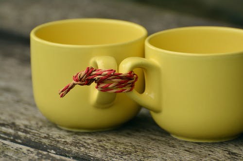 Two Yellow Mugs Tied Together With Rope