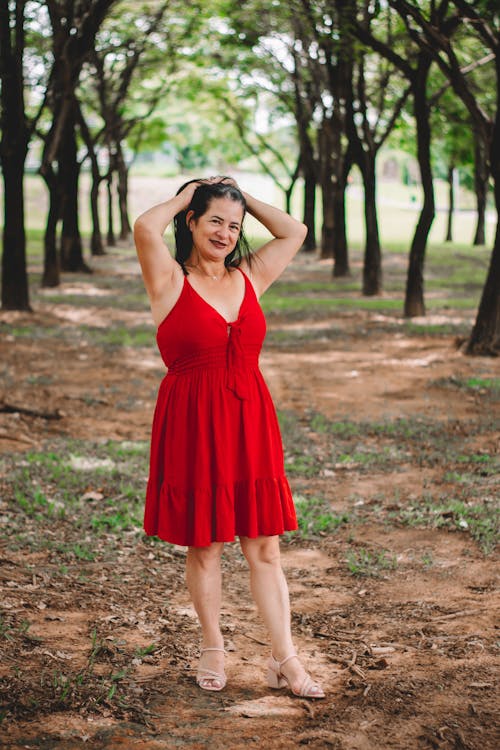 A woman in a red dress posing in the woods