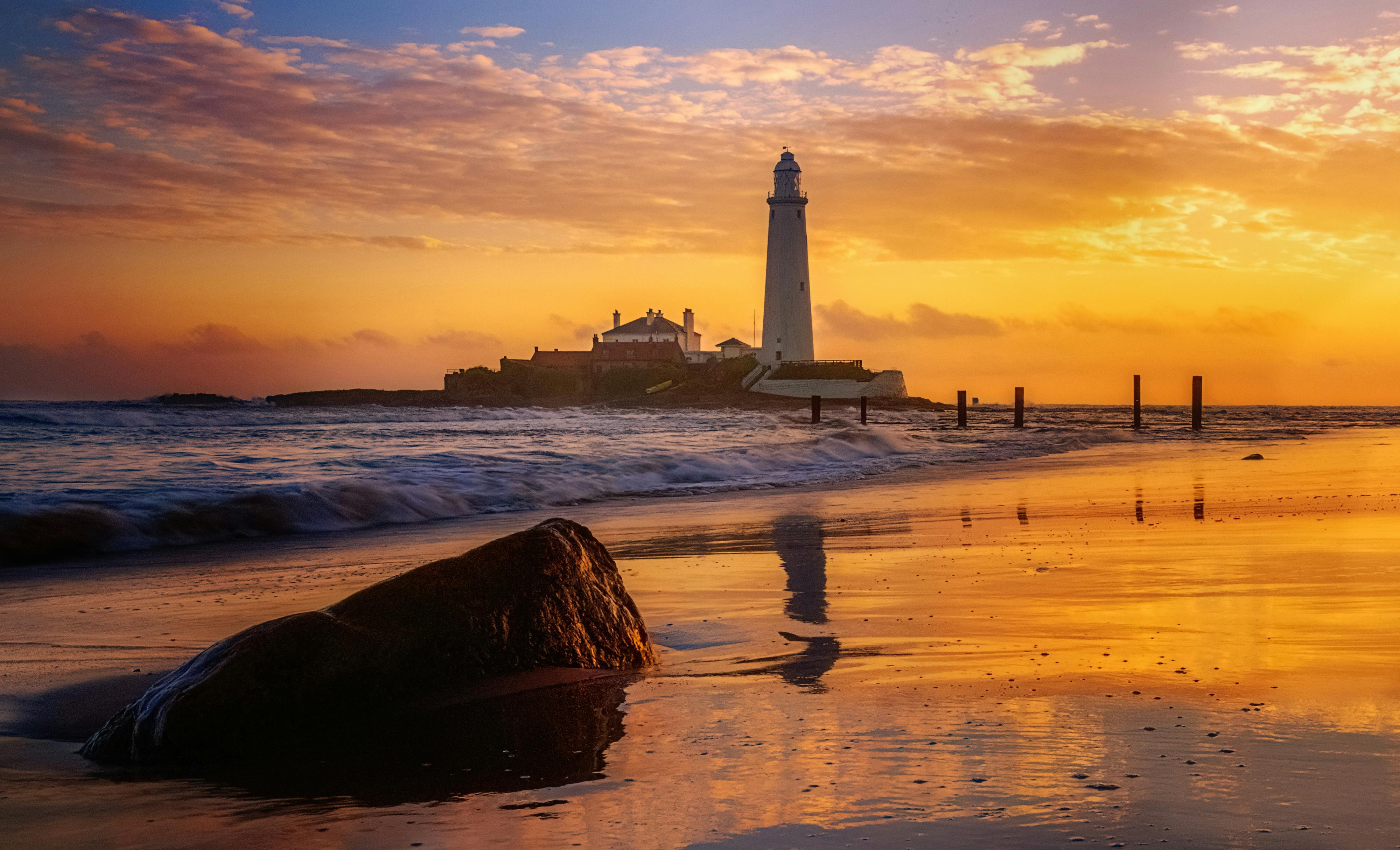 Beautiful sunset at St Mary's Lighthouse on a serene seashore in the UK.