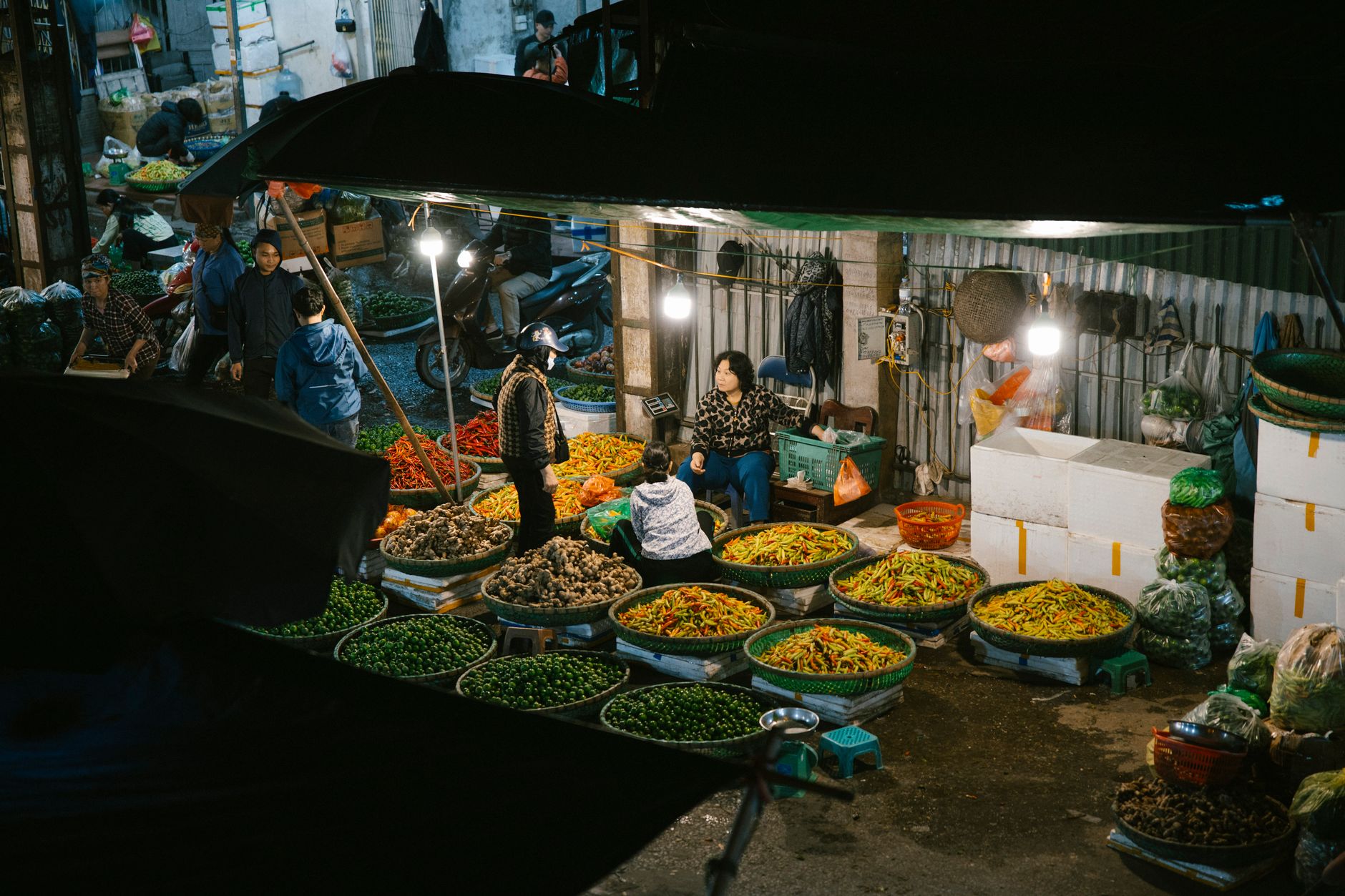 A lively night market stall with fresh vegetables and shoppers captured in an ambient setting.