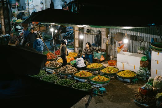 A lively night market stall with fresh vegetables and shoppers captured in an ambient setting.