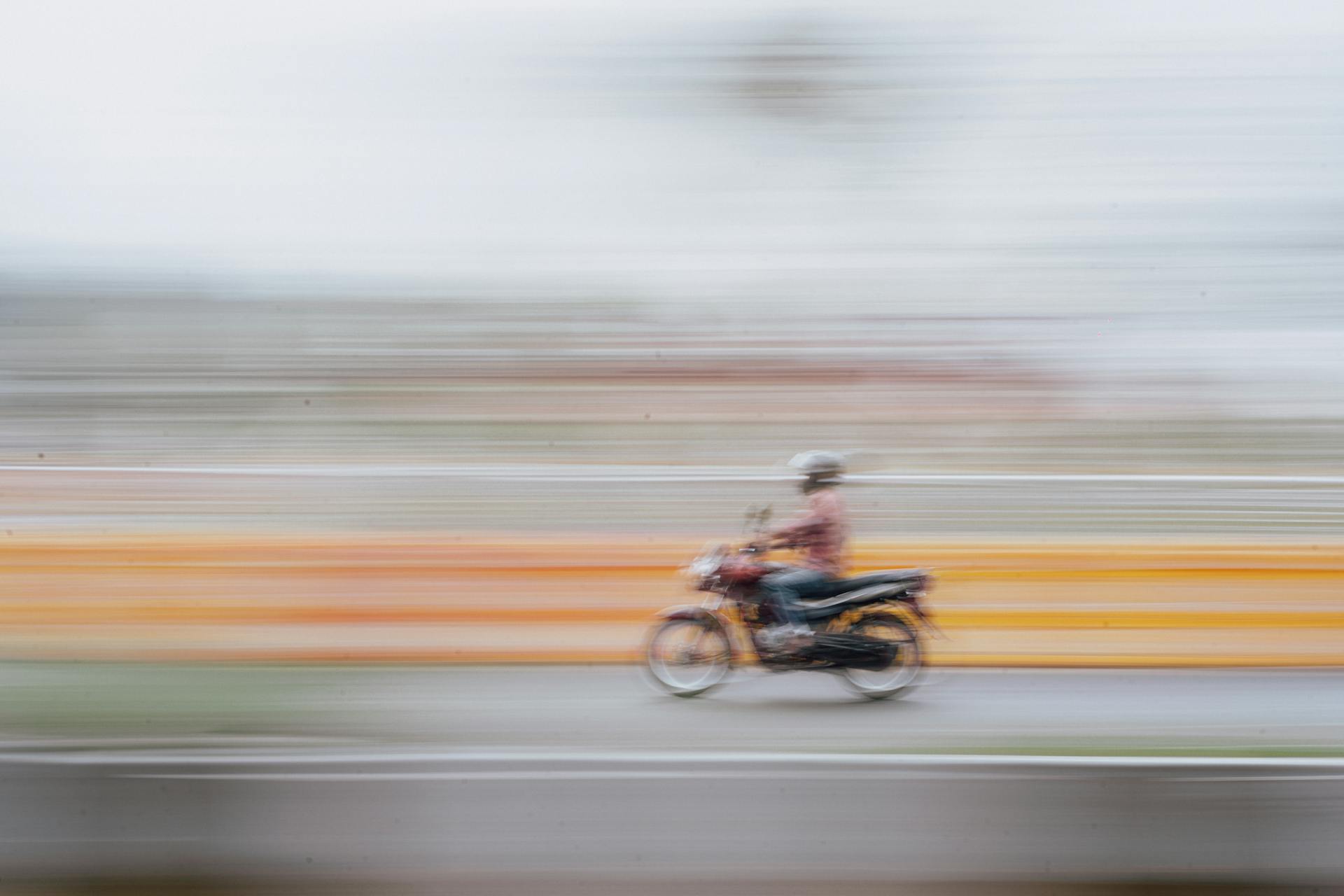 Dynamic shot of motorcyclist speeding down a road in Mysuru, India, capturing movement and motion blur.