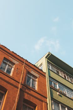 Low angle view of two colorful apartment buildings under a clear blue sky.