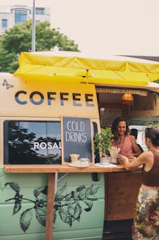 Cheerful vendor serving beverages at a vibrant coffee van outdoors.