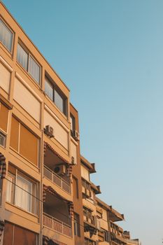 Modern apartment building with warm colors under a clear blue sky.