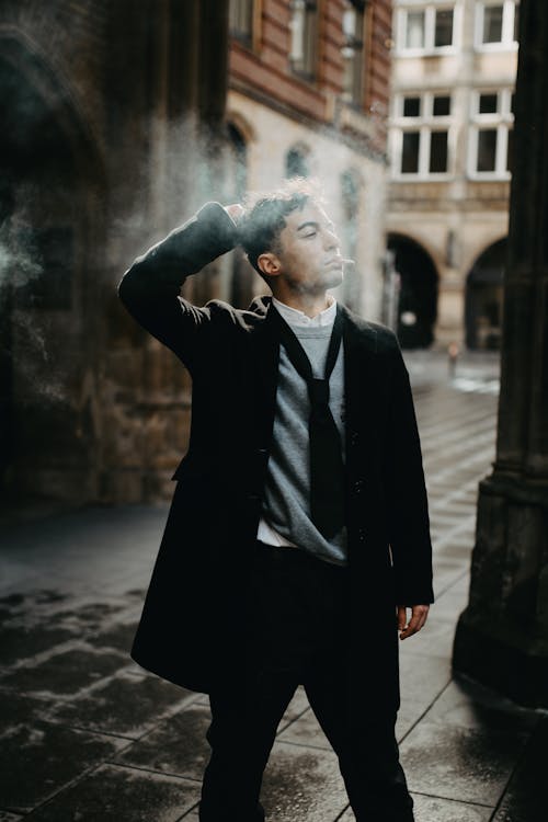 A man in a coat and tie smoking