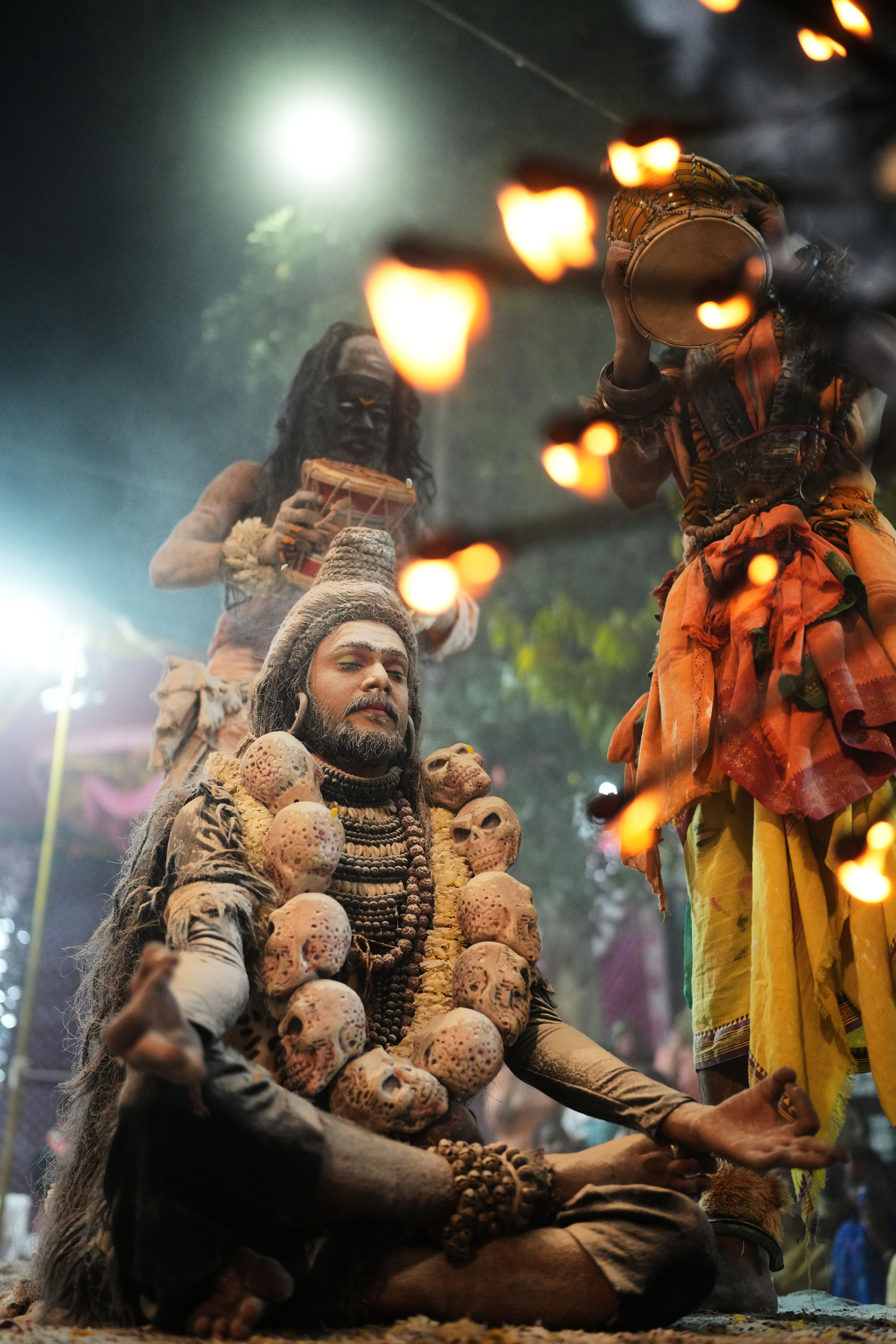 A man in traditional attire performing a spiritual ritual with others in a mystical atmosphere.