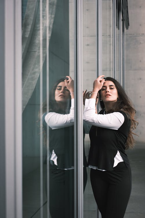 A woman in business attire leaning against a glass wall