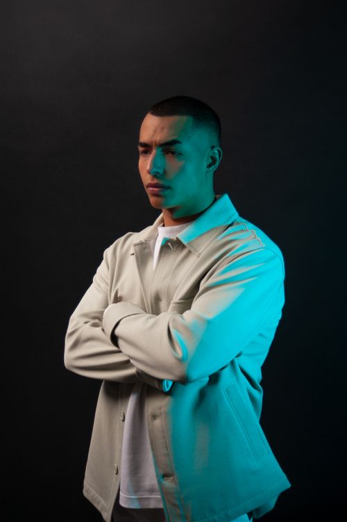 Free Portrait of a man with arms crossed, wearing a jacket, set against a dark background in a studio. Stock Photo