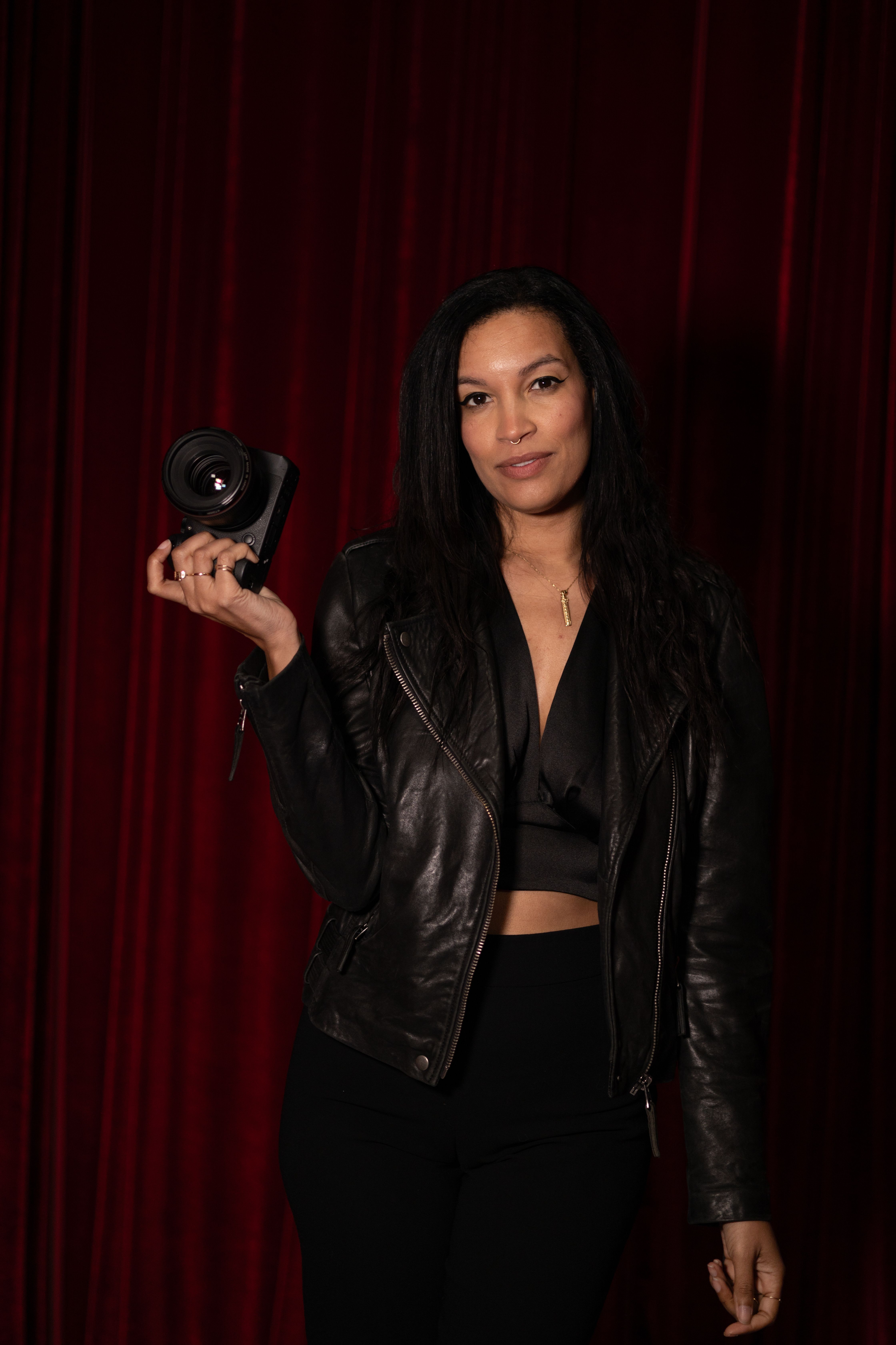 Standing Woman in Black Leather Jacket Holding Camera · Free Stock Photo