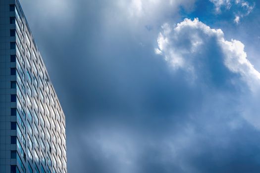A modern high-rise building set against a dramatic cloudy sky, capturing urban architecture.