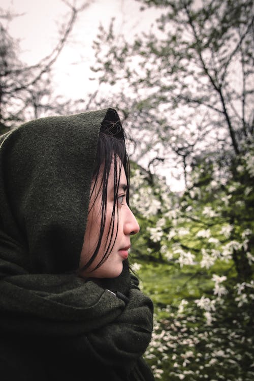 A woman in a green hoodie looking at flowers