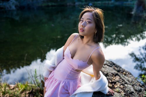 Young Asian Woman Dress Sunset Sitting on Rock Lake Background