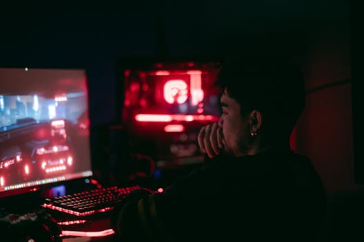 Man playing a video game on a desktop with glowing red and blue lights.