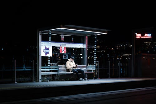 A man sitting at a bus stop at night