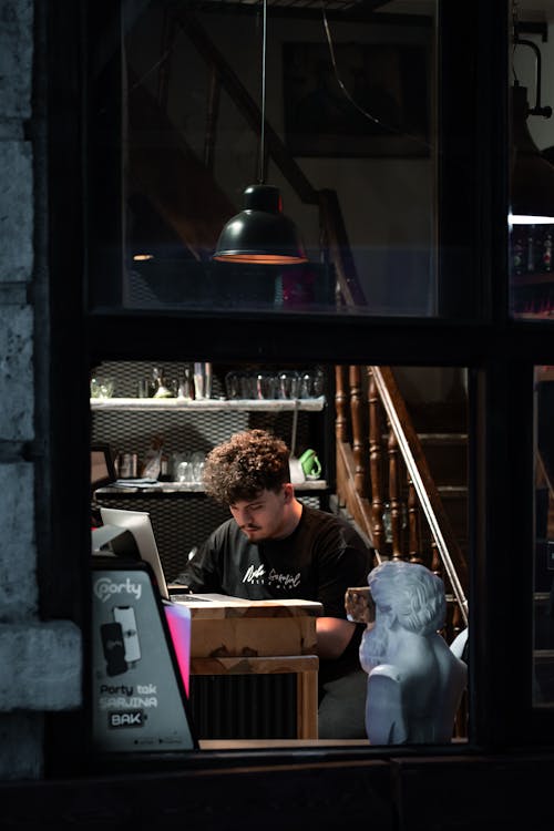 Window View of a Man working in his Workshop 