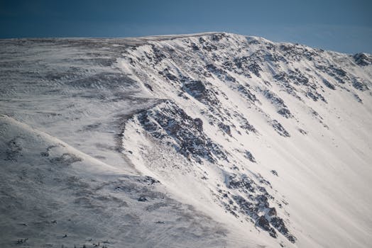 A breathtaking view of a snow-covered mountain under a clear blue sky, highlighting winter's beauty.