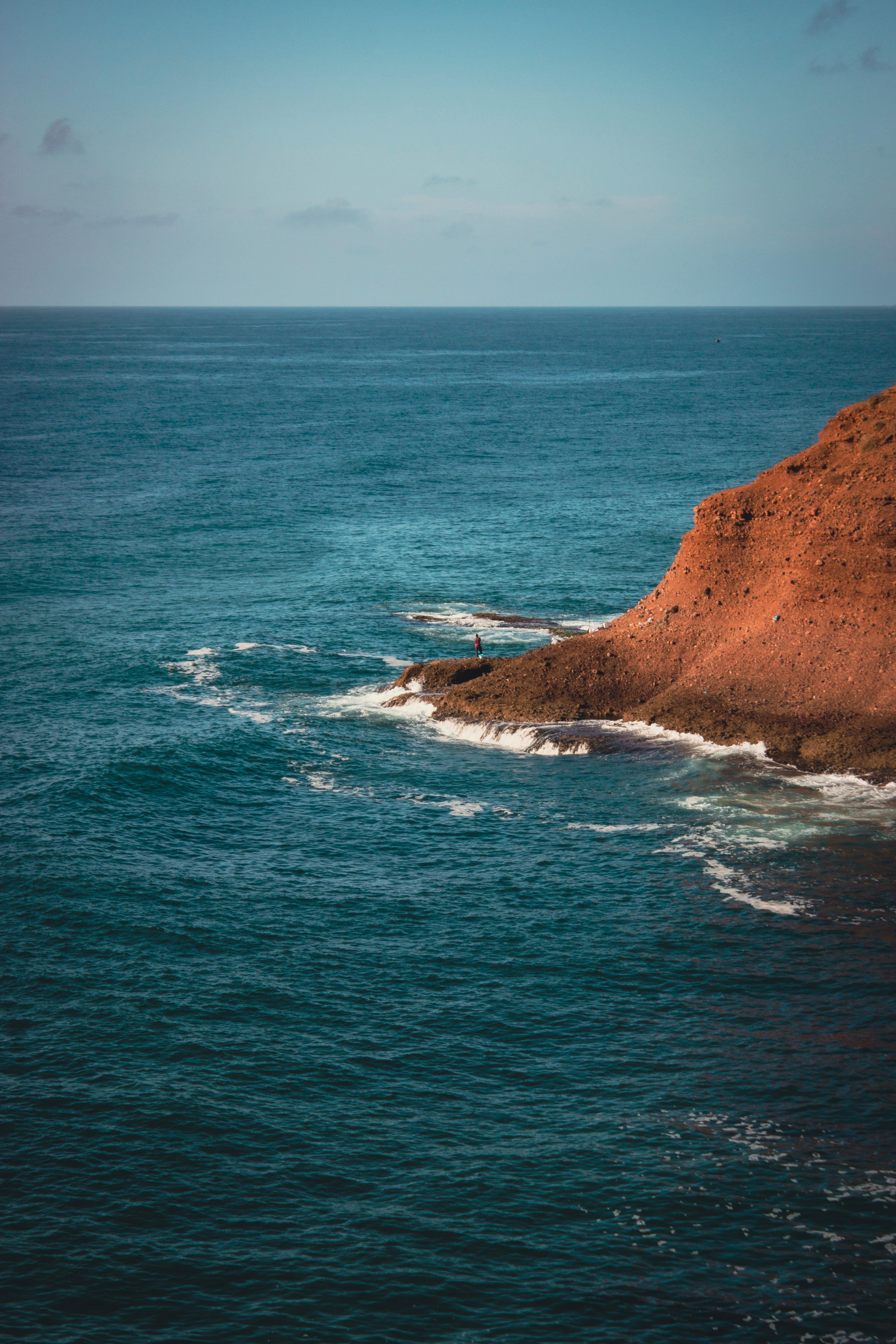 A dramatic ocean view with rugged cliffs and a vibrant horizon at sunset.