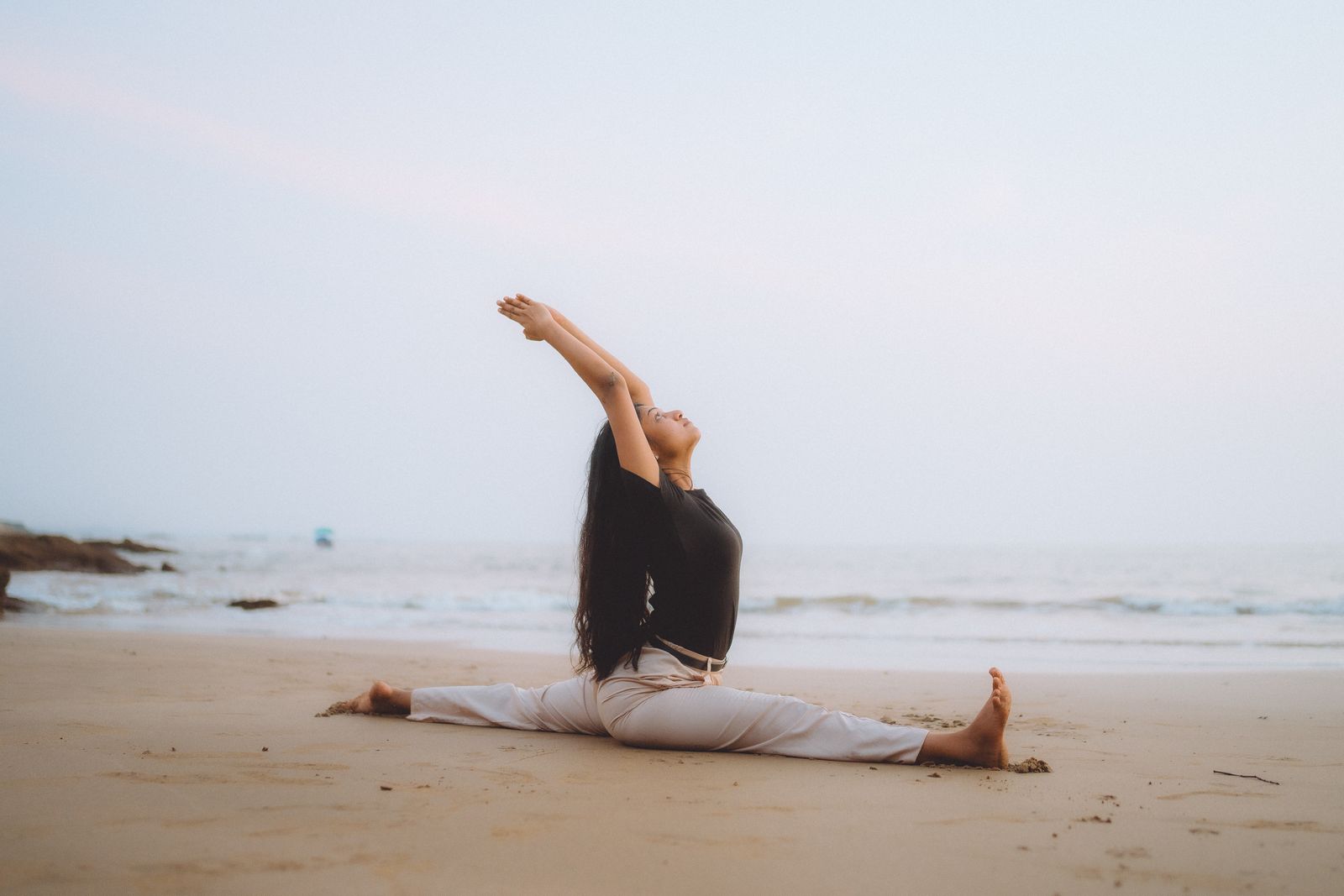 Woman practicing yoga splits pose outdoors during sunrise for flexibility and balance
