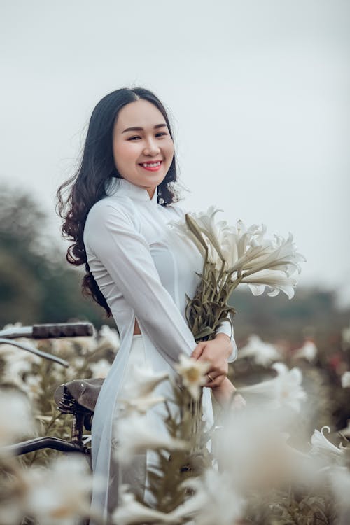Woman Wearing White Long-sleeved Dress While Holding Flowers