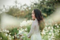 在宁静的花园里，一位白衣女子捧着一束百合花，散发着优雅与宁静