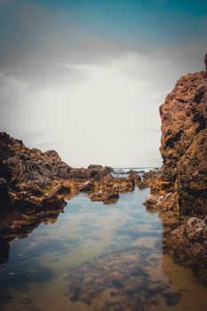 Explore the rugged beauty of a rocky coastline with reflective tide pools, showcasing nature's eroded formations and vibrant 