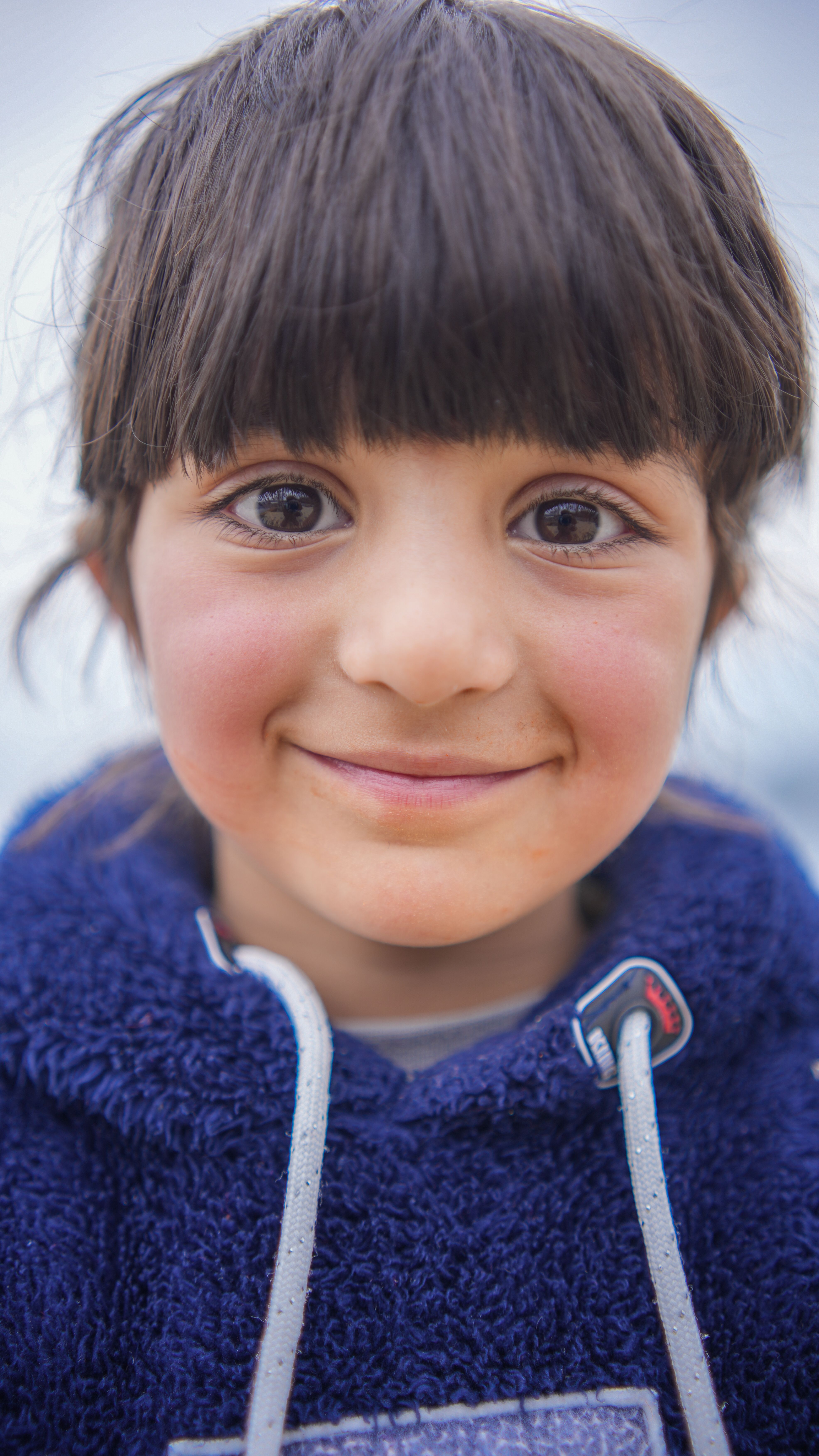 Close-up portrait of a smiling child wearing a blue hoodie in Srinagar.