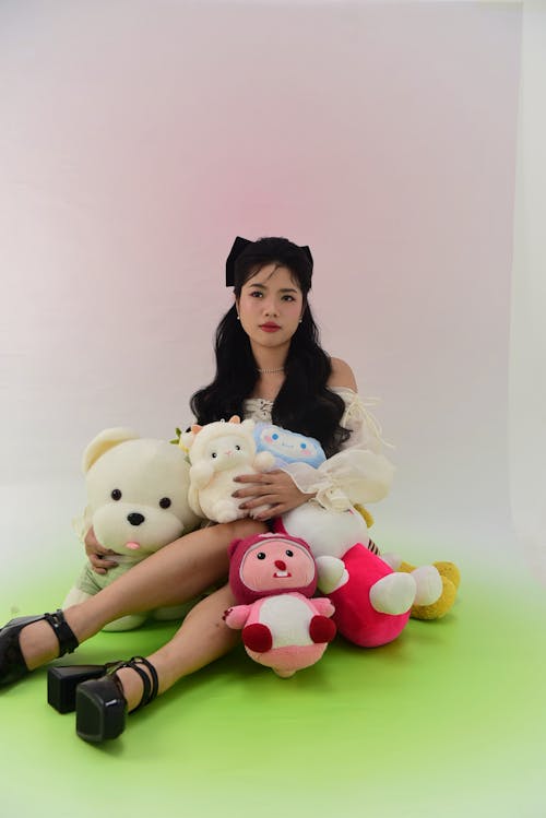 Brunette Posing with Teddy Bears against a Pastel Coloured Background