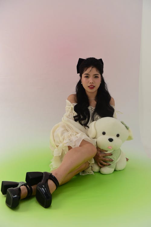 Brunette Posing with a Teddy Bear against a Pastel Coloured Background