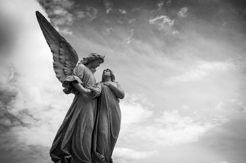 Grayscale Photography of Angel Statue Under Cloudy Skies