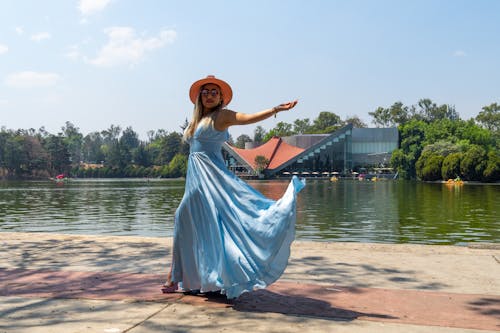 A woman in a blue dress is standing near a lake