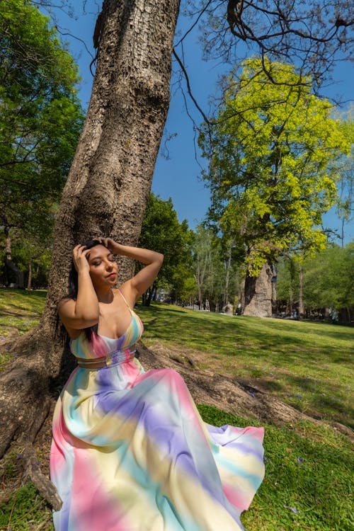 A woman in a colorful dress sitting under a tree