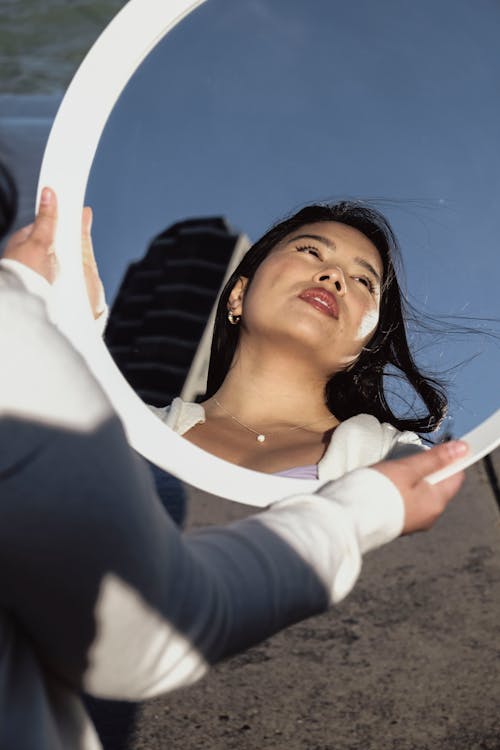 A woman looking in a mirror with her hand