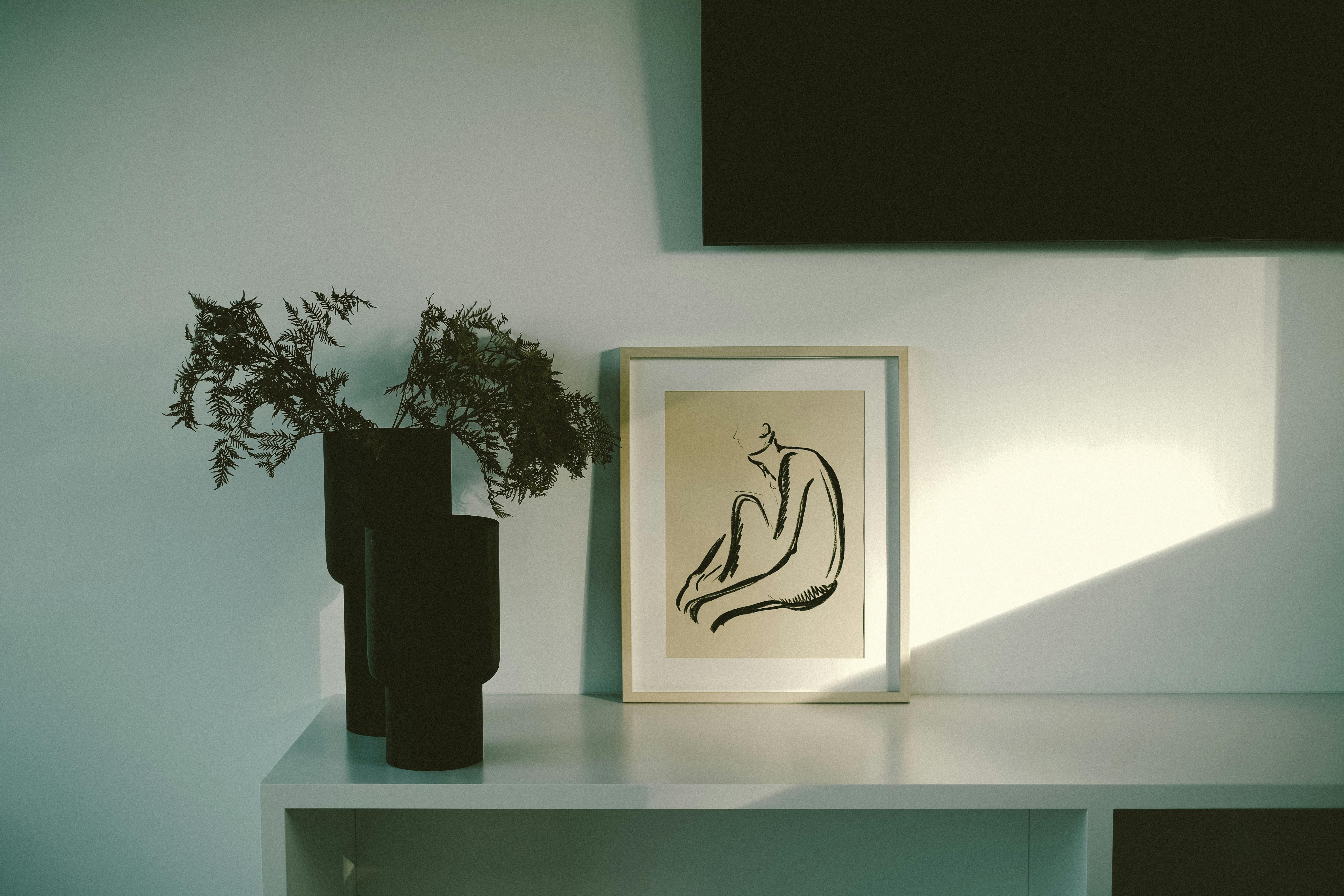 Cozy minimalist interior with abstract art and vases on a shelf.