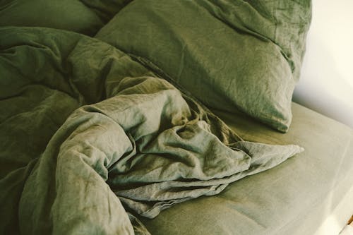 A green comforter on a bed with pillows