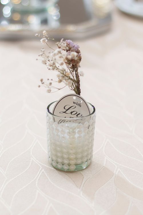 Free Glass candle holder with dried flowers on a white tablecloth, perfect for decoration. Stock Photo