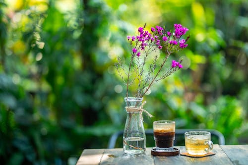 Two cups of coffee and a purple flower on a table